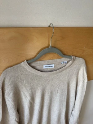 Beige tröja från Jack Jones - Säljer en stilren beige skön tröja från Jack & Jones. Perfekt för en avslappnad look. Tröjan har en enkel design med rund hals och är tillverkad i ett mjukt material. Helt oanvänd! Nypris:899kr, bara höra av sig vid frågor! XS men passar även S