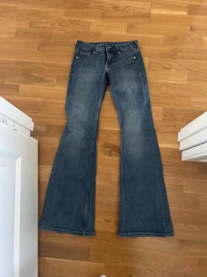 Blåa utsvängda jeans bootcut - Säljer ett par blåa jeans med bootcut och utsvängda ben. Jeansen är lågmidjade och stretchiga, vilket gör att de formar sig efter kroppen. Priset går att diskutera. 