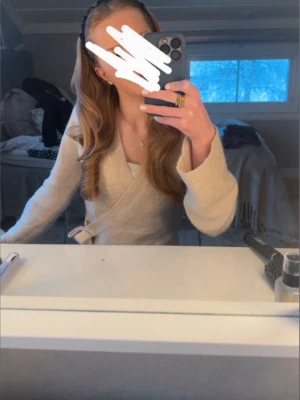 Beige omlottkofta med knytband - Säljer en beige omlottkofta med knytband i midjan. Koftan har långa ärmar och en mjuk, stickad känsla som ger en avslappnad men ändå stilren look. Perfekt att slänga över en topp för en enkel och snygg outfit. Pris går att diskutera💕