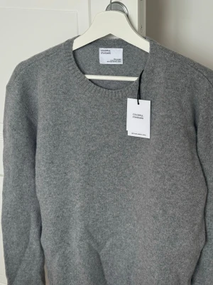 Colorful Standard Merinoull Crewneck  - Helt ny oanvänd grå stickad tröja från Colorful Standard i återvunnen merinoull. Tröjan har rund halsringning, ribbade muddar vid ärmslut och nederkant samt en enkel, stilren design som passar till allt. Köpt från Care Of Carl, nypris 1199.  Armlängd: 51	 Bröstvidd: 52	 Bottenvidd: 43	 Plagglängd: 63