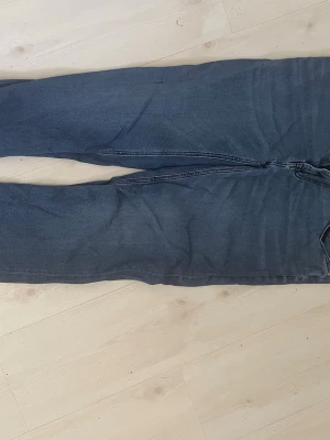 Blå slim fit jeans från Dressmann - Säljer ett par blå slim fit jeans från Dressmann. Klassisk femficksmodell med dragkedja och knapp i midjan. Jeansen har en snygg tvättad look och raka ben. Perfekta för dig som gillar en smalare passform.