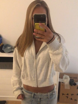 Ljusgrå zip hoodie med huva - Säljer en ljusgrå hoodie med dragkedja och huva. Hoodien har en croppad passform, långa ärmar och ribbade muddar. Perfekt till jeans eller mjukisbyxor för en chill look. Materialet känns mjukt och bekvämt. Storlek M men sitter som en xs🩷