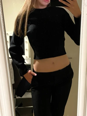 Svart croppad ribbad topp - Säljer en svart croppad topp med lång ärm och ribbad struktur. Toppen har en tight passform. Tröjan är i storlek XS men den är stretchig och jag skulle säga att den även passar S.Vid funderingar hör av er. Priset kan diskuteras.💕✨