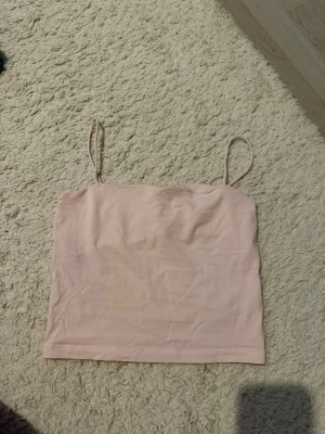 Ljusrosa linnetopp från Gina Tricot - Säljer en enkel och stilren ljusrosa linnetopp från Gina Tricot. Toppen har tunna axelband och ärmlös design, perfekt för varma dagar. Materialet känns mjukt och lätt mot huden. Passar till många olika outfits! Skulle säga att linnet slutar lite över naveln