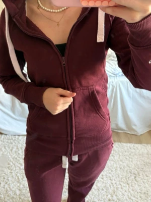 Hela vinröda russe merch - Säljer ett par vinröda mjukisbyxor med vita dragsnören i midjan. Byxorna har en avslappnad passform och är gjorda i mjukt bomullsmaterial. Perfekta för chill dagar hemma eller när du vill vara bekväm. Matcha med hoodie för en komplett look.