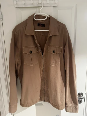 Beige overshirt från Morris - Säljer en riktigt snygg overshirt från Morris. Den är i väldigt bra skick utan några synliga defekter skick 9/10. Strl är L men passar mig som vanligtvis har M Priset är ej hugget i sten så bara att skriva vid minsta lilla.