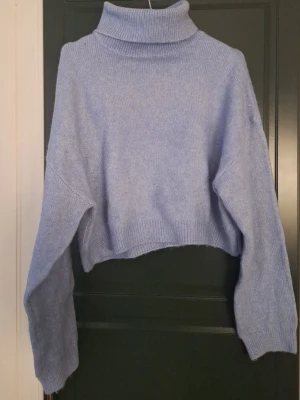 Ljusblå croppad polotröja stickad - Superfin ljusblå stickad polotröja med croppad passform och långa ärmar. Ribbad kant vid ärmslut, nederkant och krage.