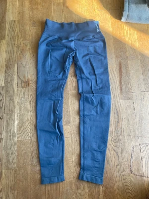 DFYNE impact grå S - Snygga blå leggings från Doymus med seamless design och hög midja. Stretchigt material som sitter skönt och formar sig efter kroppen. Perfekta för träning eller chill dagar. Diskret logga vid linningen och långa ben.