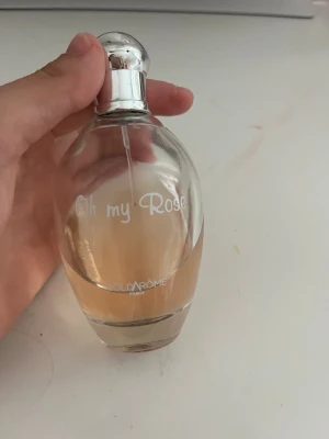 Oh my Rose parfym i glasflaska - Oh my Rose parfym från SoldaRÔME Paris i en elegant, genomskinlig glasflaska med rundad form och silvrig kork. Parfymen har en ljusrosa nyans som ger en fräsch och feminin känsla. Perfekt för dig som gillar blommiga dofter.