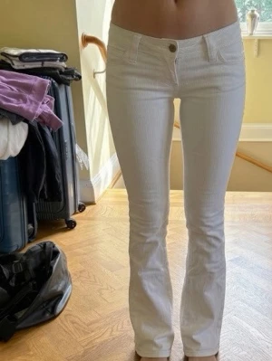 Vita bootcut jeans med låg midja -  Snygga vita jeans med bootcut-modell och låg midja. Jeansen har klassiska fem fickor och stängs med knapp och dragkedja. Perfekta för en fräsch och trendig look, passar till det mesta och är riktigt bekväma.