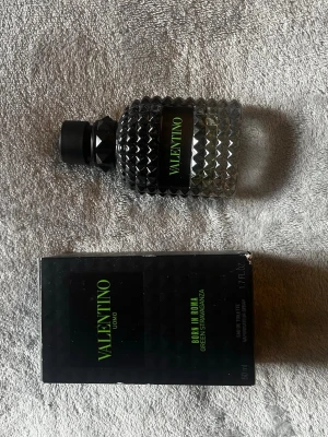 Valentino Uomo Born In Roma parfym - Valentino Uomo Born In Roma Green Stravaganza är en exklusiv herrparfym i en stilren, transparent glasflaska med nitar och svart lock. Flaskan har en modern design med gröna detaljer och medföljande svart kartong. Perfekt för dig som gillar lyxiga dofter.