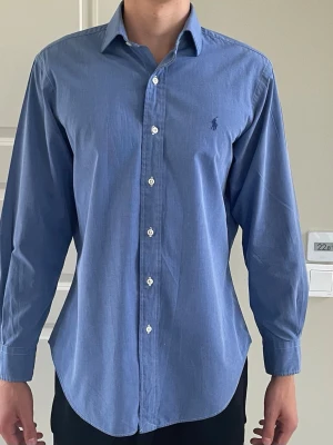 Blå skjorta från ralph lauren - Klassisk blå skjorta med lång ärm och knappar framtill. Skjortan är storlek M men passar även S