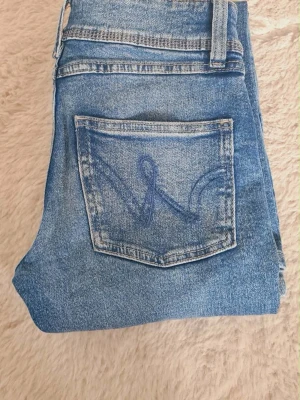Blå bootcut jeans med broderad ficka - Säljer ett par ljusblåa midwaist bootcut jeans med snygg broderad bakficka. Jeansen har klassisk femficksdesign.❤️strl 152