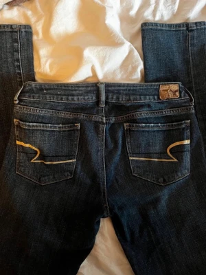 American Eagle jeans, lågmidjade  - Snygga och tidlösa mörkblå jeans från American Eagle 🤍 Mörkblå (något ljusare i verkligheten än på bilderna) Låg midja Storlek: 4 (motsvarar ca S/M) Passform: Figurnära med klassisk jeanskänsla Straight Skick: HeltSkick: Helt nya (köpta via Sellpy men aldrig använda) – inga hål eller fläckar ✨ 100 % original  📦 Skickas snabbt 🤍 Mängdrabatt vid köp av flera plagg – kolla gärna min profil!