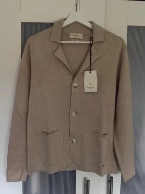 Beige och marinblå cardigan från MARK-UP - Perfekta till en utekväll på stan med polarna. Två stilfulla men ändå casual cardigans från MARK-UP i marinblå och beige. Dessa cardigans har klassisk krage, tre knappar framtill och två fickor. Tillverkade i 100% viskos som ger en len känsla mot huden. 