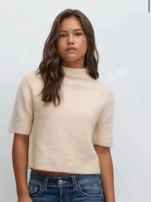 Beige stickad tröja med halv polo - Mysig beige stickad tröja med halv polokrage och korta ärmar. Tröjan har en boxig passform och är perfekt för lager på lager. Passar till både jeans och kjol för en avslappnad look.