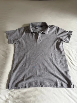 Race Marine Piké Slim fit - Snygg grå pikétröja från Race Marine i slim fit med korta ärmar och klassisk krage. Framtill finns en diskret broderad RM-detalj. Tröjan har knappar vid halsen för en bekväm känsla.