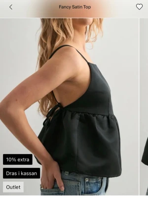 Svart satin topp från Nelly - Snygg svart satin topp från Nelly med ärmlös design och knyt i sidan. Toppen har en lätt utsvängd passform och slät yta som ger en lyxig känsla. Perfekt att styla med jeans eller kjol för en trendig look. Aldrig Andvänd lappar kvar 