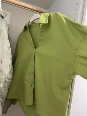 Grön oversized skjorta i bomull - Snygg grön skjorta i oversized modell med klassisk krage och knappar framtill. Tillverkad i mjuk bomull och har långa ärmar. Perfekt att styla lager på lager eller bära som den är.