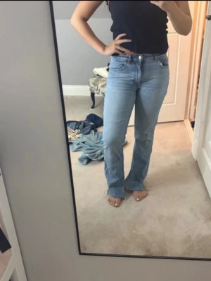 Ljusblå raka jeans med hög midja - Säljer ett par ljusblå jeans med rak/bootcut passform och medel hög midja. Jeansen har klassisk femficksdesign och stängs med knapp och dragkedja. Perfekta till en avslappnad och trendig look.