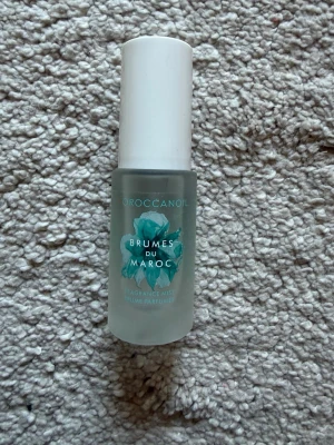 Moroccanoil  parfym - Fräsch doftmist från Moroccanoil, Brumes du Maroc. Flaskan är frostad med vit kork och har en turkos blomillustration på framsidan. Perfekt att ha i väskan för en snabb uppfräschning under dagen.