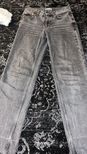 Grå raka jeans med fem fickor - Säljer ett par grå jeans med raka ben. Jeansen har en normal passform och är tillverkade i ett slitstarkt denimtyg.
