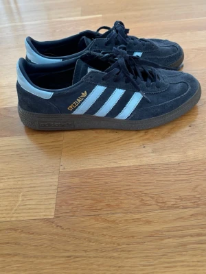 Adidas Spezial sneakers mörkblå - Säljer ett par Adidas Spezial sneakers i mörkblå mocka med ljusblå ränder och detaljer. Klassisk retrostil med gummisula och guldfärgad Spezial-logga på sidan. Perfekta för dig som gillar streetwear och sportig look.