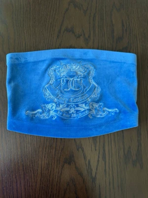 Blå tube top från   Juicy Couture - Blå tube top i mjuk velour från Juicy Couture. Topen  har ett broderat emblem med krona och texten 'Juicy Couture' 
