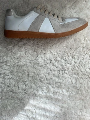 Vita och grå sneakers med mockadetaljer - Maison Martin margielas i bra skick. Box ingår storlek 43 fast passar 42