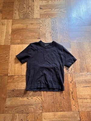 Svart topp från Gina Tricot - En svart topp från Gina Tricot med rund halsringning och korta ärmar. 💘Enkel och stilren design som passar till många olika looks. tröjans botten har en vågig söm! sparsamt använd med inga tecken!❣️