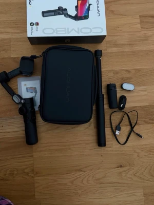 Svart kamerastabiliseringskit - Komplett kit med svart kamerastabiliserare, teleskopstång, tripod, USB-kabel, förvaringsväska och tillbehör. Perfekt för att filma med mobilen och få stabila videor. Allt är i stilren svart design och tillverkat i plast och metall.Tripod är lite fastnad men det kvittar.