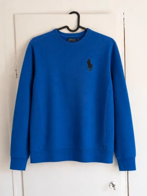 Ralph Lauren sweatshirt - Säljer en snygg sweatshirt från Polo Ralph Lauren i en klarblå färg med svart Big Pony-logga på bröstet. En sportig och stilren tröja som passar perfekt till både vardag och fritid. ✔️ Original från Polo Ralph Lauren ✔️ Broderad Big Pony-logga ✔️ Bekväm passform ✔️ Mjuk och högkvalitativ kvalitet Storlek: L (14-16) Skick: 7/10, den är i bra skick men lite sliten!
