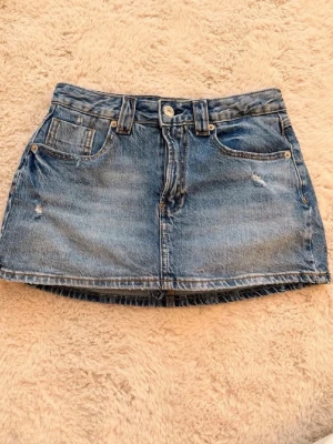 Jeanskjol - Säljer en snygg blå jeanskjol i kort modell med slitna detaljer från stradivarius, den är i storlek 40 men sitter som en 38 då stradivarius storlekar är väldigt små i storlek
