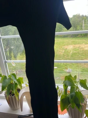 Svart ribbad långklänning - Säljer en svart ribbad klänning med korta ärmar. Går typ till knäna. Klänningen har en kroppsnära passform och är tillverkad i ett stretchigt material som framhäver siluetten. Perfekt för dig som gillar en stilren och enkel look.