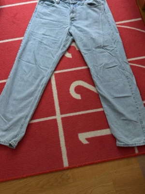 Ljusblå loose fit jeans Jack & Jones - Ljusblå jeans från Jack & Jones i loose fit-modell. Klassisk femficksdesign med dragkedja och knapp. Tillverkade i denim med avslappnad passform och raka ben. Perfekta för en chill och avslappnad stil. Har några snöfläckar men knappast märkbara!