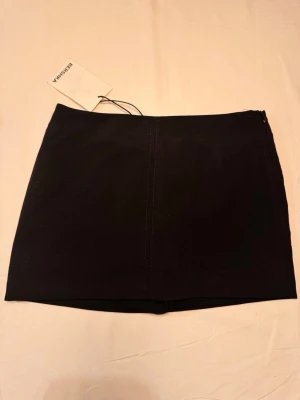 Svart skrots från Bershka - svart skrots från Bershka med enkel design och rak passform. Kjolen har en diskret dragkedja i sidan och är tillverkad i ett mjukt material som ger en snygg siluett. Midjemått 33cm, Längd 30cm