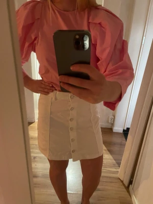 Vit kortkjol med knappar från g perfect jeans - Snygg vit kortkjol från g perfect jeans i jeansmaterial. Kjolen har raka linjer, knappar framtill och en klassisk midjehöjd. Perfekt att matcha med färgglada toppar för en trendig look.