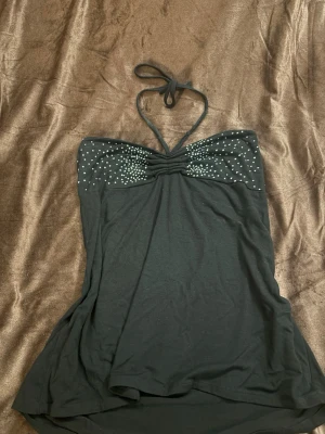 Svart halterneck topp med strass - Snygg svart halterneck topp från SVS Collection. storlek L men jag skulle säga att den är som en M. har strassdetaljer över bysten och knyt i nacken. 