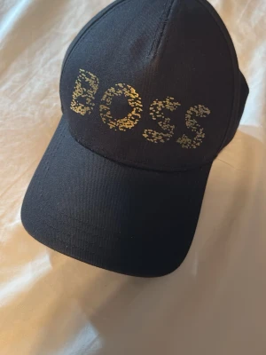 Hugo boss keps - Säljer en Hugo Boss-keps i fint skick. Modellen säljs inte längre. Inga hål eller skador. Justerbar storlek.