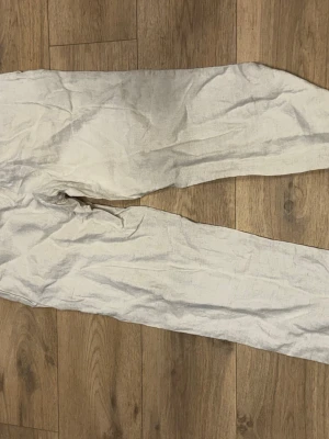 Vita linnebyxor med resårmidja - Säljer ett par vita linnebyxor med rak passform och resår i midjan. Perfekta för varma dagar och ger en avslappnad look. Byxorna är tunna och luftiga, vilket gör dem riktigt sköna att bära.