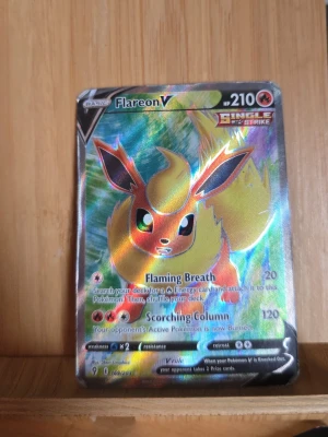 Pokémonkort Flareon V Single Strike - Säljer ett holografiskt Pokémonkort med Flareon V från Single Strike-serien. Kortet har färgstark design med Flareon i rött, gult och orange mot en skimrande bakgrund. Perfekt för samlare eller Pokémonfans som vill utöka sin kortlek.