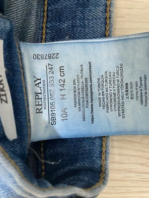 Blå jeans från Replay, slim - Säljer ett par ljusblå jeans från Replay med raka ben och klassisk femficksmodell. Jeansen har en snygg tvättad look och kontrastsömmar. Passar dig som är ca 142 cm lång. Perfekta till vardags för en avslappnad stil. Är slim jeans och passar någon som är ungefär 10-11