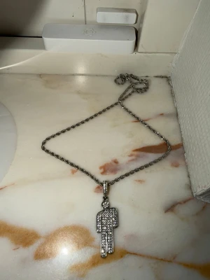 Silverfärgat halsband med blohsh berlock - INTE officiell merch! Halsbandet har en kedja på cirka 50 cm och själva blohshen är 4 cm. Materialen är zinc och rostfritt stål. Halsbandet skiner fint med silver gems! Aldrig använt 🖤