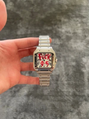 Seiko Mod Santos “F*ck 9–5” – Silver - ✨ Specifikationer Modell: Seiko Mod Santos ⌚ Urverk: Automatiskt Seiko-urverk Gångreserv: 41 timmar ⏳ Boett: Rostfritt stål med borstade och polerade ytor Storlek: 40 mm 📏 Glas: Reptåligt safirglas 💎 Urtavla: Vit tavla med romerska siffror och röd “F*ck 9–5”-text 🔥