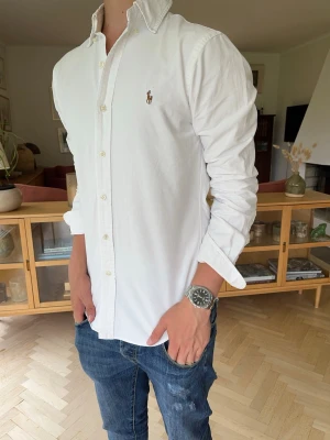 Ralph Lauren skjorta vit slim fit herr - Stilren vit Ralph Lauren Oxford-skjorta med ikonisk broderad Polo Pony-logga. En garderobsklassiker som passar till allt – perfekt för jobb, fest, skola eller en elegant vardagslook. Lätt att matcha och alltid aktuell. Mycket bra skick!! Storlek S (slim fit)  #RalphLauren #PoloRalphLauren #Oxford #VitSkjorta #Skjorta #OldMoney #QuietLuxury #Preppy #BusinessCasual #SmartCasual #Designer #Herr #Classic #Elegant #Mode #Kvalitet #Jeans #Chinos #Minimalist #Timeless