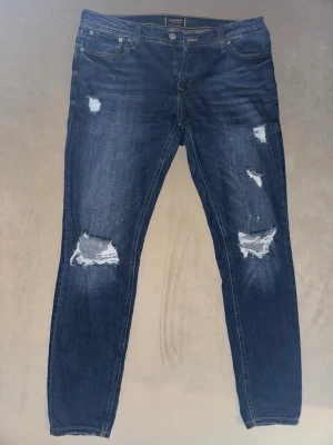 Jack & Jones Intelligence med reva W34/L30 - Säljer mina mörkblå Jack & Jones-jeans i modellen Spray On/Tom, storlek W34/L30. Jeansen har bekväm passform med stretch och passar både till vardag och fest. Dem är i mycket fint skick och endast använda ett fåtal gånger. Säljs pga att dem har blivit för små för mig.