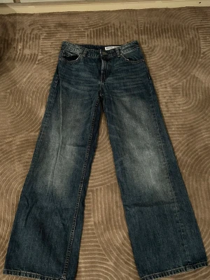 Blåa loose fit jeans med vida ben - Säljer ett par blåa jeans med loose fit och riktigt vida ben. Jeansen har klassisk femficksdesign och slitna detaljer framtill för en cool, avslappnad look. 