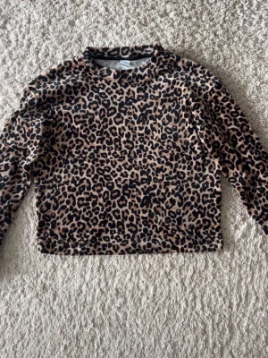 Leopardmönstrad långärmad tröja - Långärmad tröja med leopardmönster i beige och svart. Tröjan har rak passform, rund halsringning och är tillverkad i ett mjukt, stretchigt material. Perfekt för dig som gillar djurmönstrat!🐆🐆