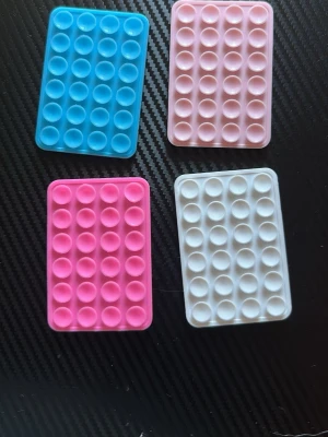 Fidget pop it mobilhållare silikon - Fyra rektangulära pop it mobilhållare i silikon, perfekta som tillbehör till mobilen. Kommer i färgerna blå, två olika rosa och vit. Flexibla och mjuka med bubblor att trycka på, ger både skydd och underhållning till din telefon. Sugproppar som fäster bra på platta ytor.