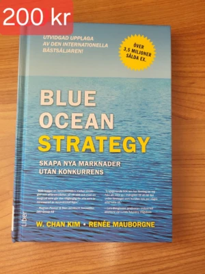 Blue Ocean Strategy bok - Säljer boken 'Blue Ocean Strategy' av W. Chan Kim och Renée Mauborgne. Boken har ett blått omslag med havsmotiv och tydlig gul och vit text. Perfekt för dig som vill lära dig om att skapa nya marknader utan konkurrens.